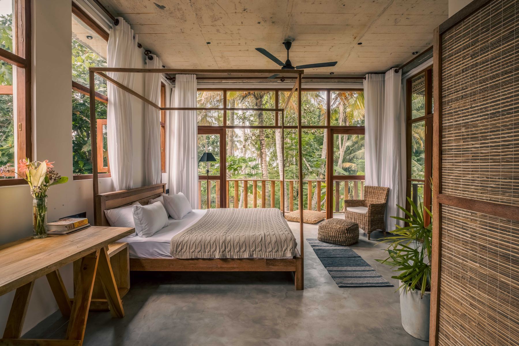 King bedroom with a four-poster teak bed and windows opening onto the veranda